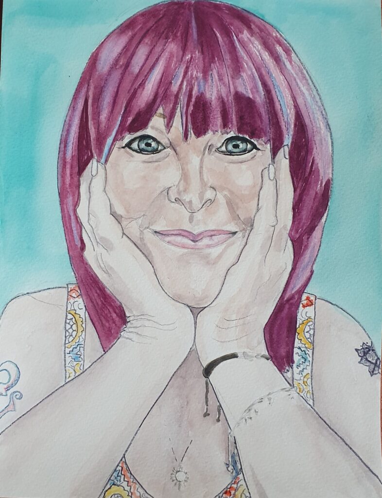 ID Good looking woman, she is smiling, she has blue eyes and is wearing dark eye liner and pink lipstick her hair is reddy/purple in colour and she has a fringe with a longish shaggy bob. She is smiling. Her face is cupped in her hands and she is wearing a thong bracelet and charm bracelet and a delicate necklace. you can see the straps of her dress and a tiny bit of the top of it, it has a small pattern on it in multicolours, The background is plain teal ,