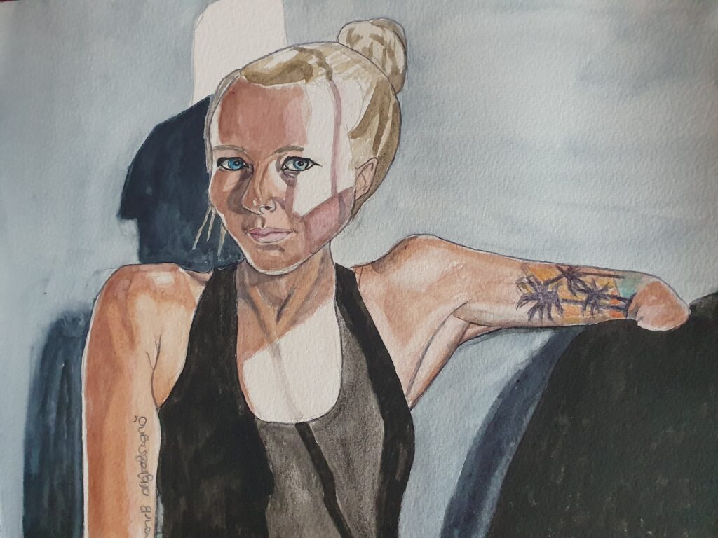 ID Portrait painting of young woman in strong light and shadow. She has blonde hair in a bun and blues eyes, she is wearing a black vest top. She has limb difference and her left arm is approx. elbow length and is resting on a cushion. She has a tattoo of a sunset on a palm beach on her arm . Her other arm is straight by her side and she has a tattoo of some writing on that arm