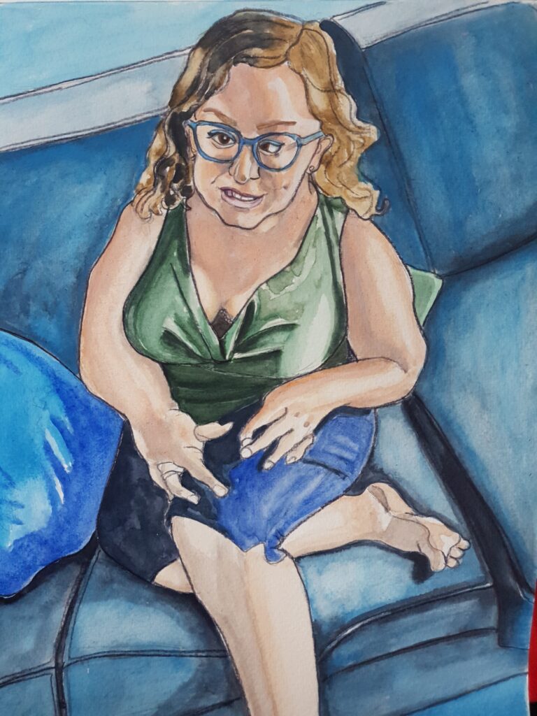 ID Watercolour portrait of petite, busty woman, she has long wavy hair and is wearing a green top and blue kneelength denim shorts. She has hand and facial differences. She is wearing blue glasses and is sat on a blue grey couch with a blue cushion nex to her and the coner of a green cushion peaking out behind her.