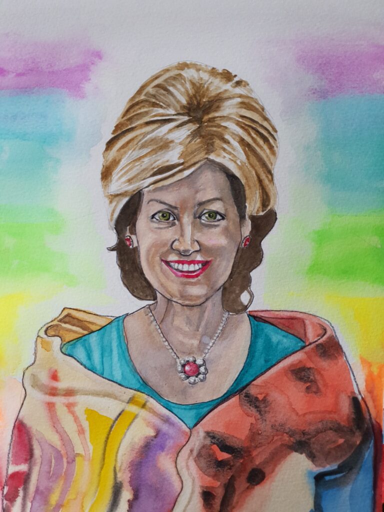 ID Attractive middle aged woman, smiling, she has dark hair underneath with bouffant blonde hair on top. She is wearing ruby and diamond earrings and necklace and a turquoise dress. She is also wearing a wrap round her shoulders which is blended multi-colours. In the background I have done her an white aura that blends into the colours of the chakras, to represent her spirituality.